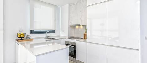 A modern kitchen with white cabinetry, a central island, and a built-in oven.