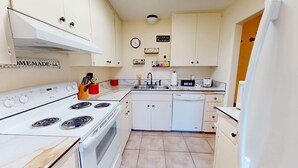 A compact kitchen with white cabinets, a stove, a sink, and a dishwasher. - NEW LISTING Right At Home-Midland Cowboy Siesta Corner Lot w/ Patio & Cov'd Park (Midland)