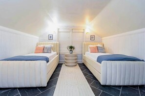 A room with two beds, a small table with a plant, and a door with a light above it. - Atlanta-Themed Home, Sleeps 7, 10 Min to Stadium & Downtown (East Point)