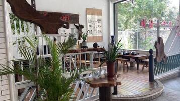 A room with a wooden table, chairs, potted plants, and a white railing.