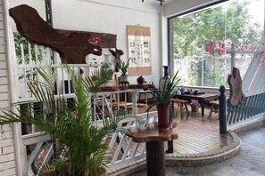 A room with a wooden table, chairs, potted plants, and a white railing. - Daxin Mingxuan Qianzhuyuan Hotel (Daxin)