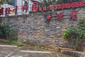 A stone wall with a sign and a contact number. - Daxin Mingxuan Qianzhuyuan Hotel (Daxin)
