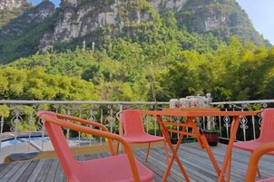 A terrace with outdoor seating and a view of a mountainous landscape.