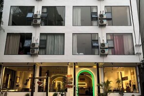 A multi-story building with air conditioning units, large windows, and a storefront with a neon sign. - Daxin Mingxuan Qianzhuyuan Hotel (Daxin)