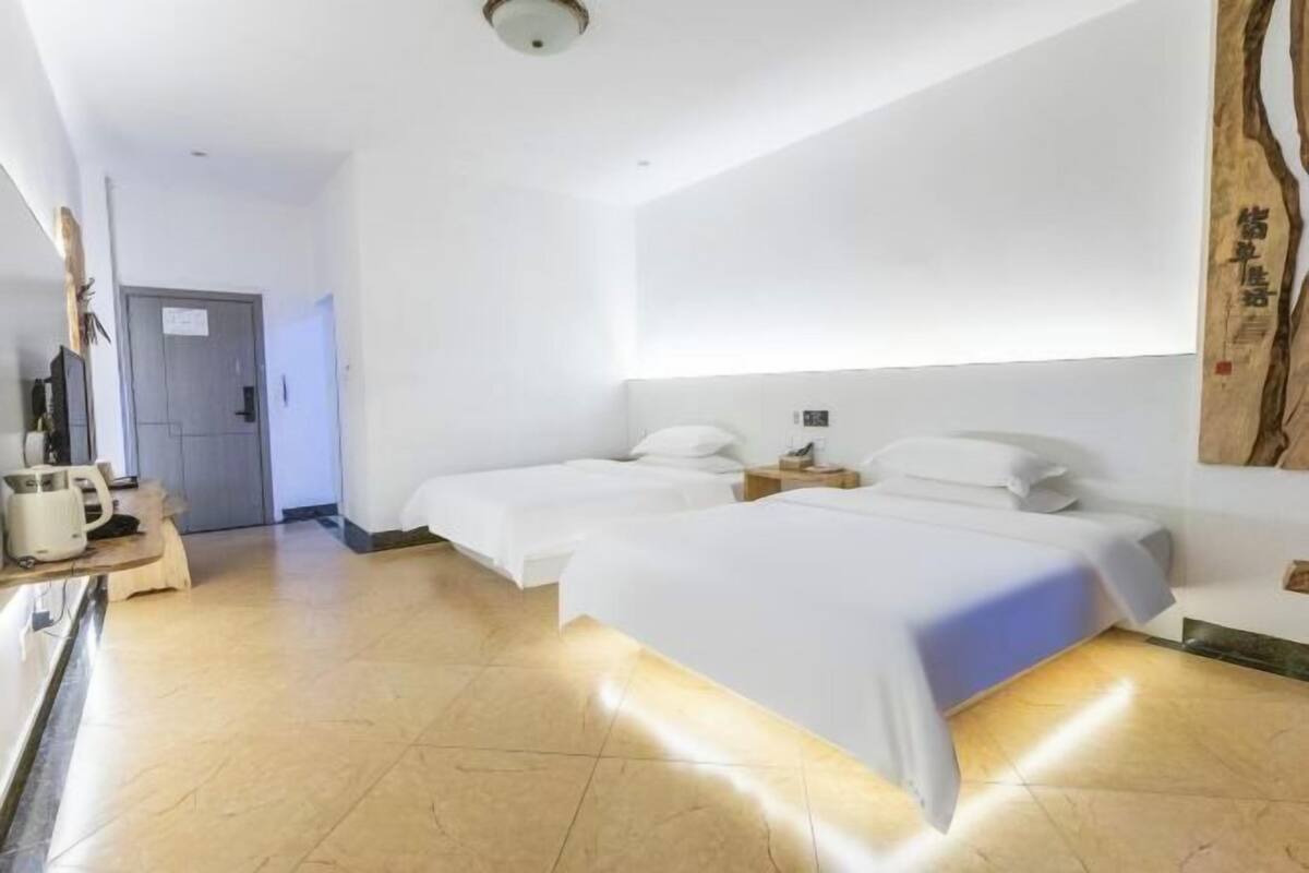 A hotel room with two beds, a small table, and a wall-mounted artwork.