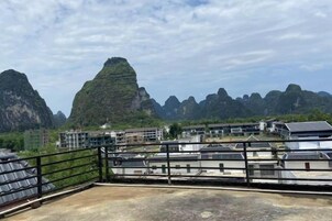 Una terraza en la azotea con vistas a montañas de piedra caliza y edificios al fondo.