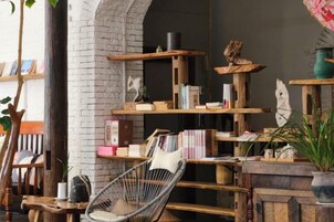 Un rincón acogedor para leer, con una butaca de mimbre, estanterías y una chimenea.