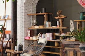 A cozy reading nook with a wicker chair, bookshelves, and a fireplace.