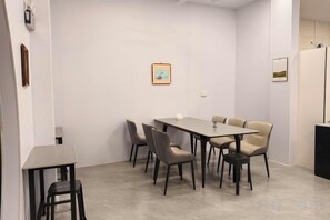 A conference room with a rectangular table, six chairs, and a small whiteboard on the wall. - Daxin Mingxuan Qianzhuyuan Hotel (Daxin)