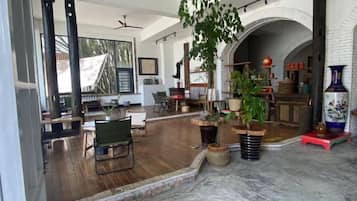 A spacious room with a wooden floor, a large plant, and a marble area.
