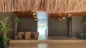 A spacious room with a thatched ceiling, wooden flooring, wicker furniture, and potted plants. - Dep 1 room, green terrace and view (Tulum)