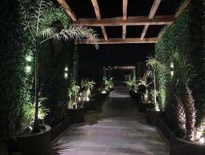 Stroll through lush surroundings, leading to a central area beneath a wooden ceiling.