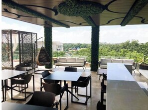 Relax in style with a hanging chair, sofas, and tables in this beautifully designed outdoor seating area overlooking a lush green landscape.