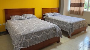 A room with two wooden beds, each with patterned bedding, a yellow wall, and a framed picture above the beds. - Royal Amazon (Coca)