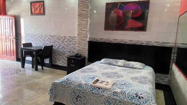 A hotel room with a bed, a desk, a chair, and a small table. - Royal Amazon (Coca)