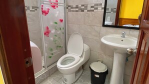 A bathroom with a toilet, sink, and a trash bin. - Royal Amazon (Coca)