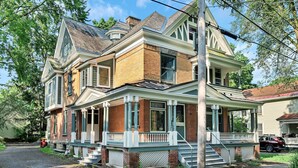 A two-story house with a porch, brick facade, and a garage.
