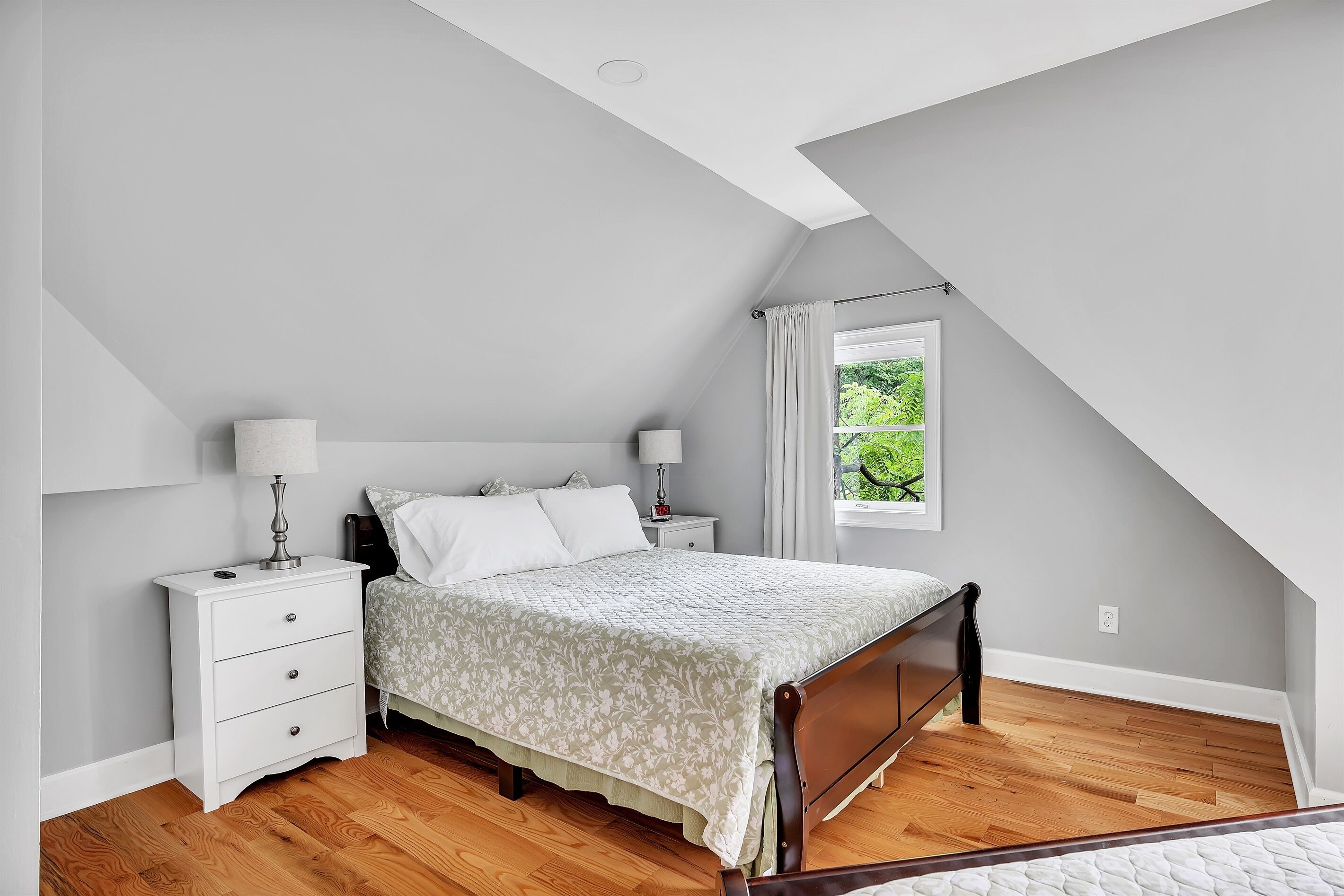 Une chambre à coucher avec un lit, des tables de chevet, une lampe et une fenêtre avec des rideaux.