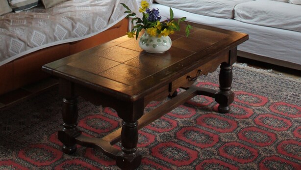 Una habitación acogedora con una mesa de madera, dos sofás blancos y una alfombra estampada.