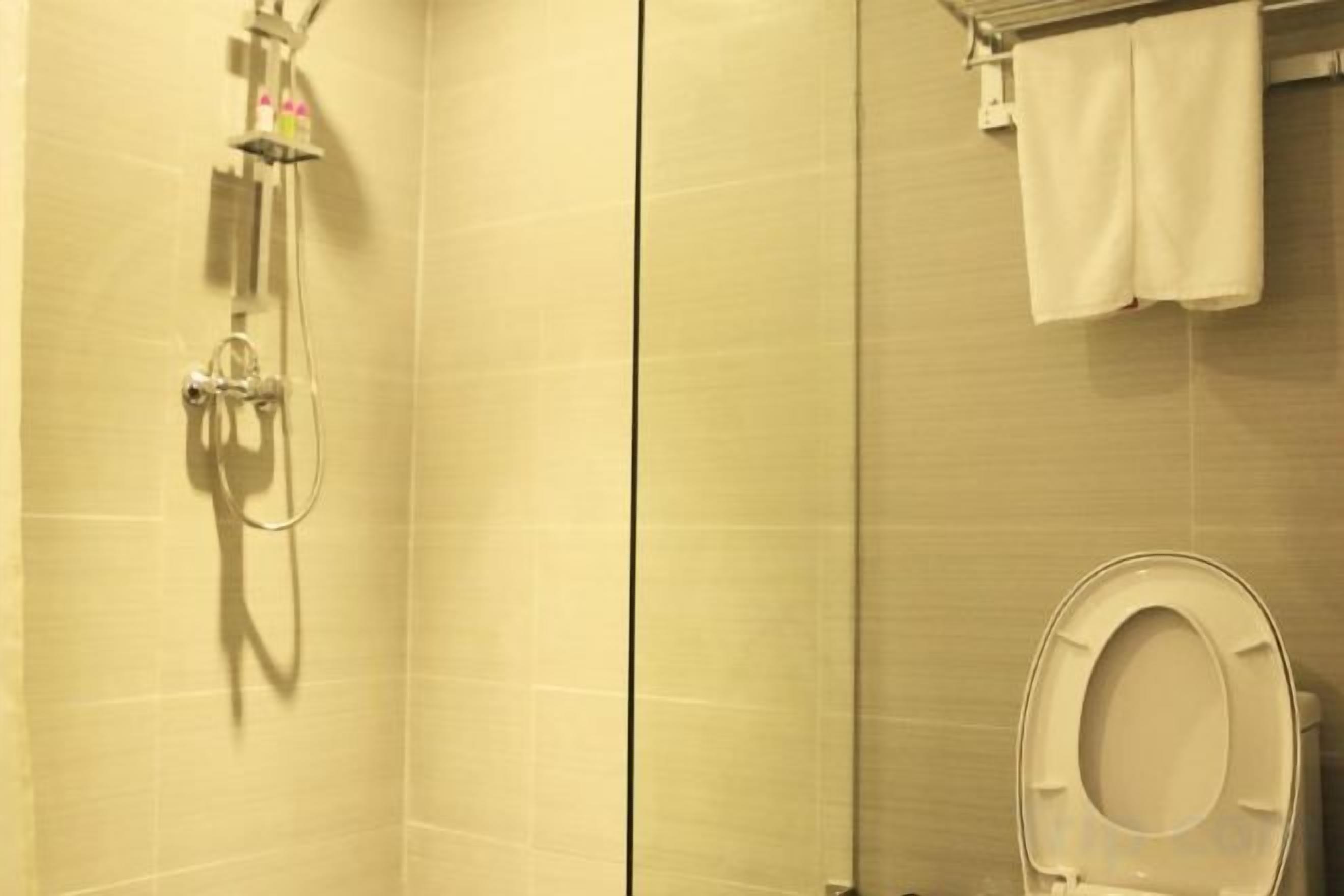 Un baño con ducha, inodoro y perchero para toallas.