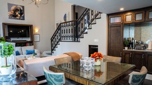 Una sala moderna con una mesa de comedor de vidrio, un sofá y una escalera.