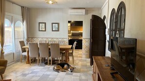 Amplia sala de estar con comedor, televisor y un perro descansando en el suelo.