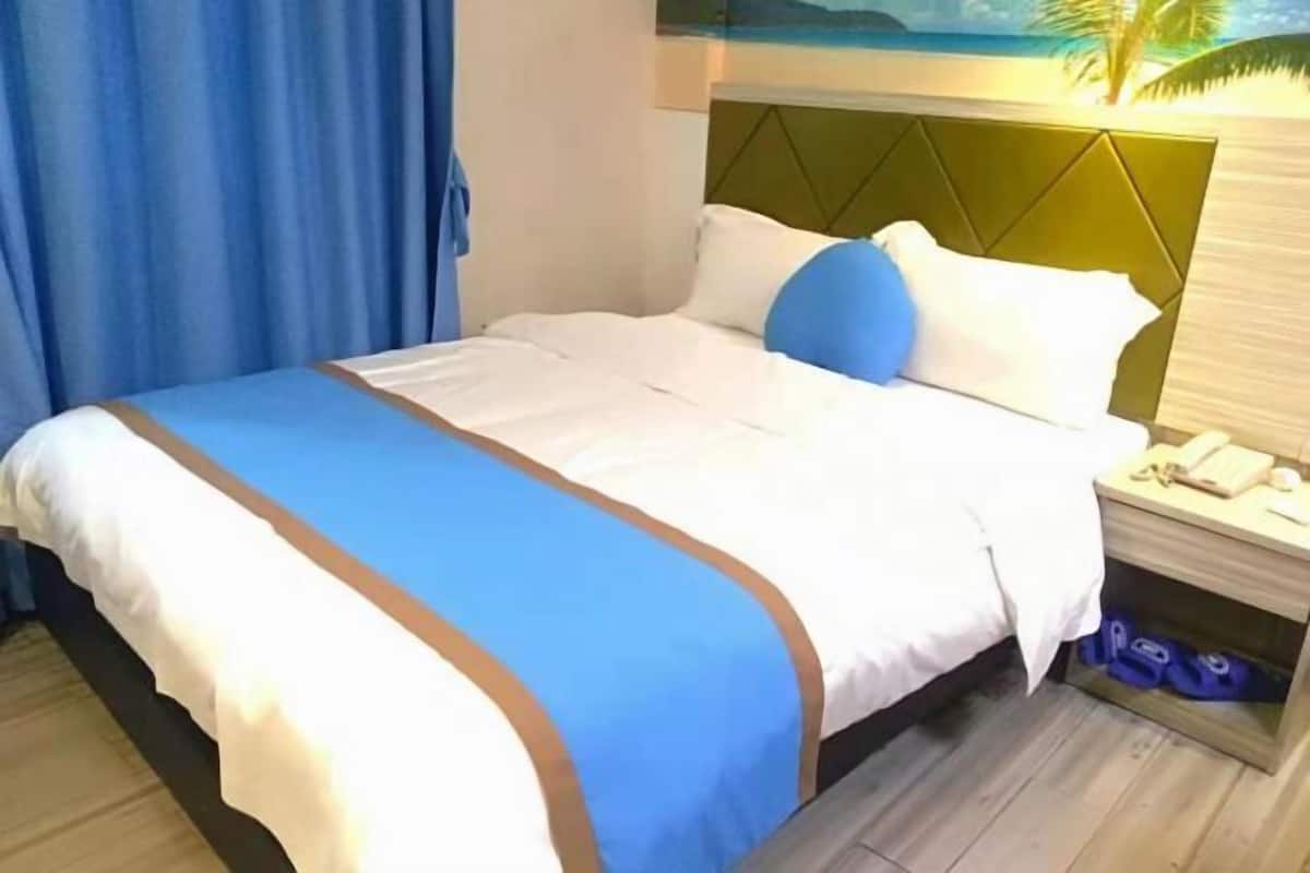 A hotel room with a bed, a nightstand, and a wall with a painting.