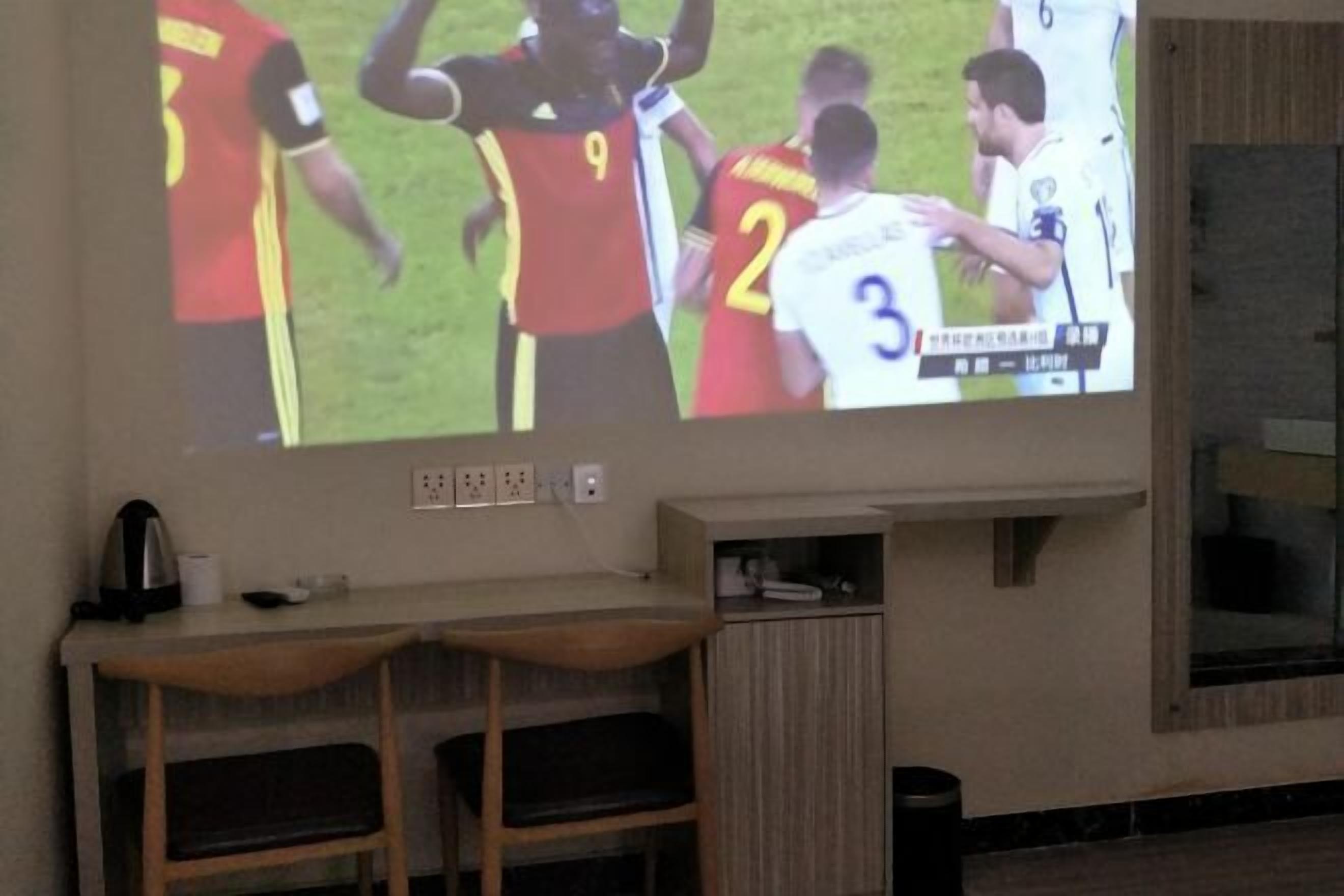 A television mounted on a wall displaying a sports event.