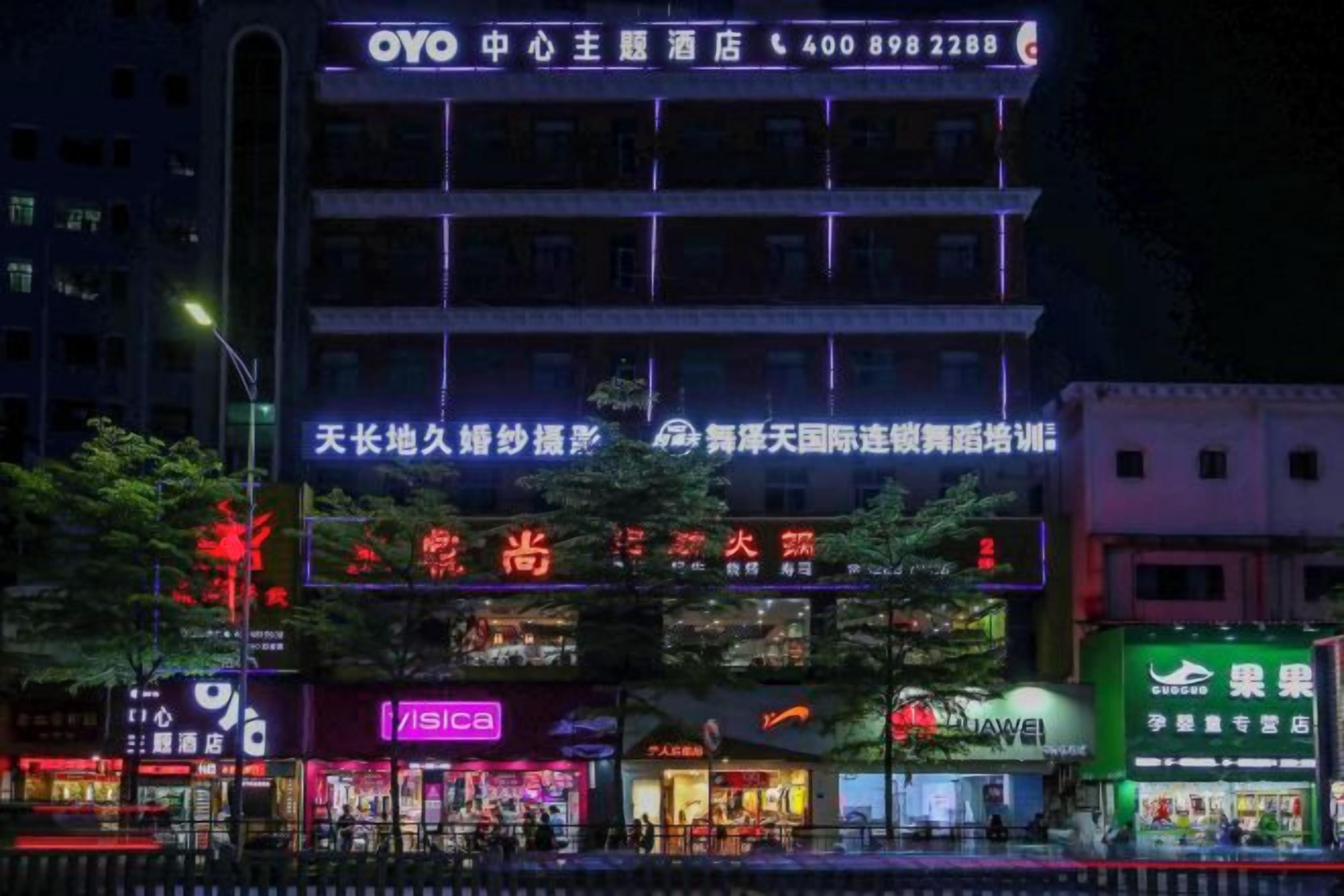 A multi-story building with illuminated signage, including a prominent OYO hotel sign.