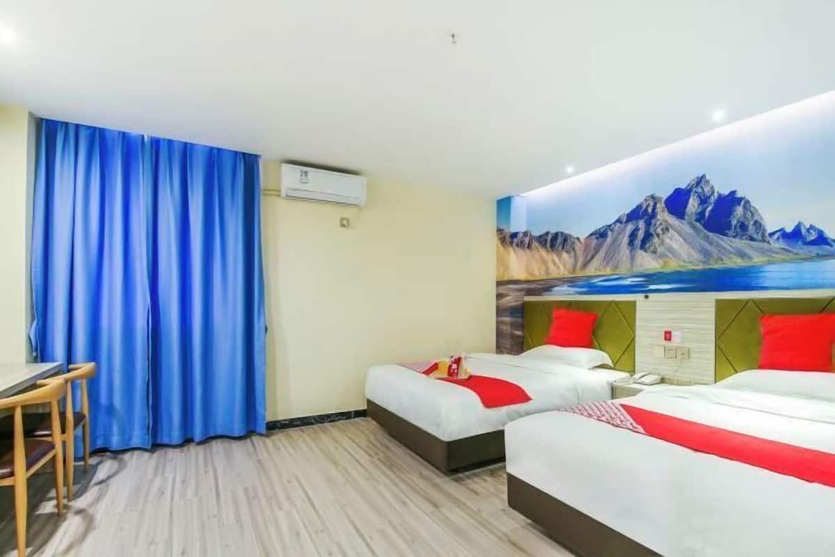 A hotel room with two beds, a desk, and a large window with curtains.
