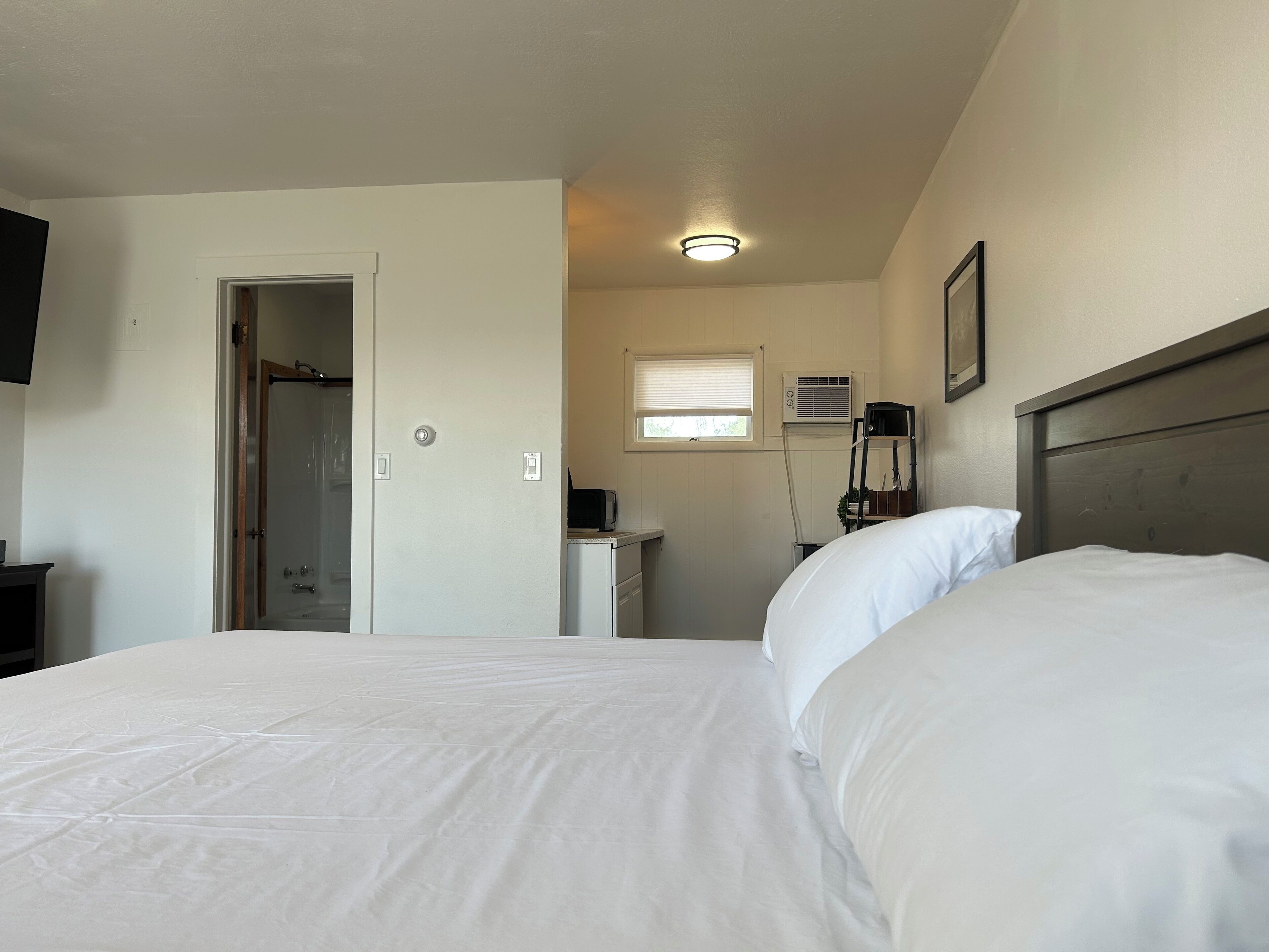 Un dormitorio con dos camas, un escritorio, una silla, un televisor y una ventana con persianas.