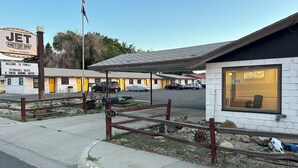 A motel with a signboard, a flag, and a covered parking area.