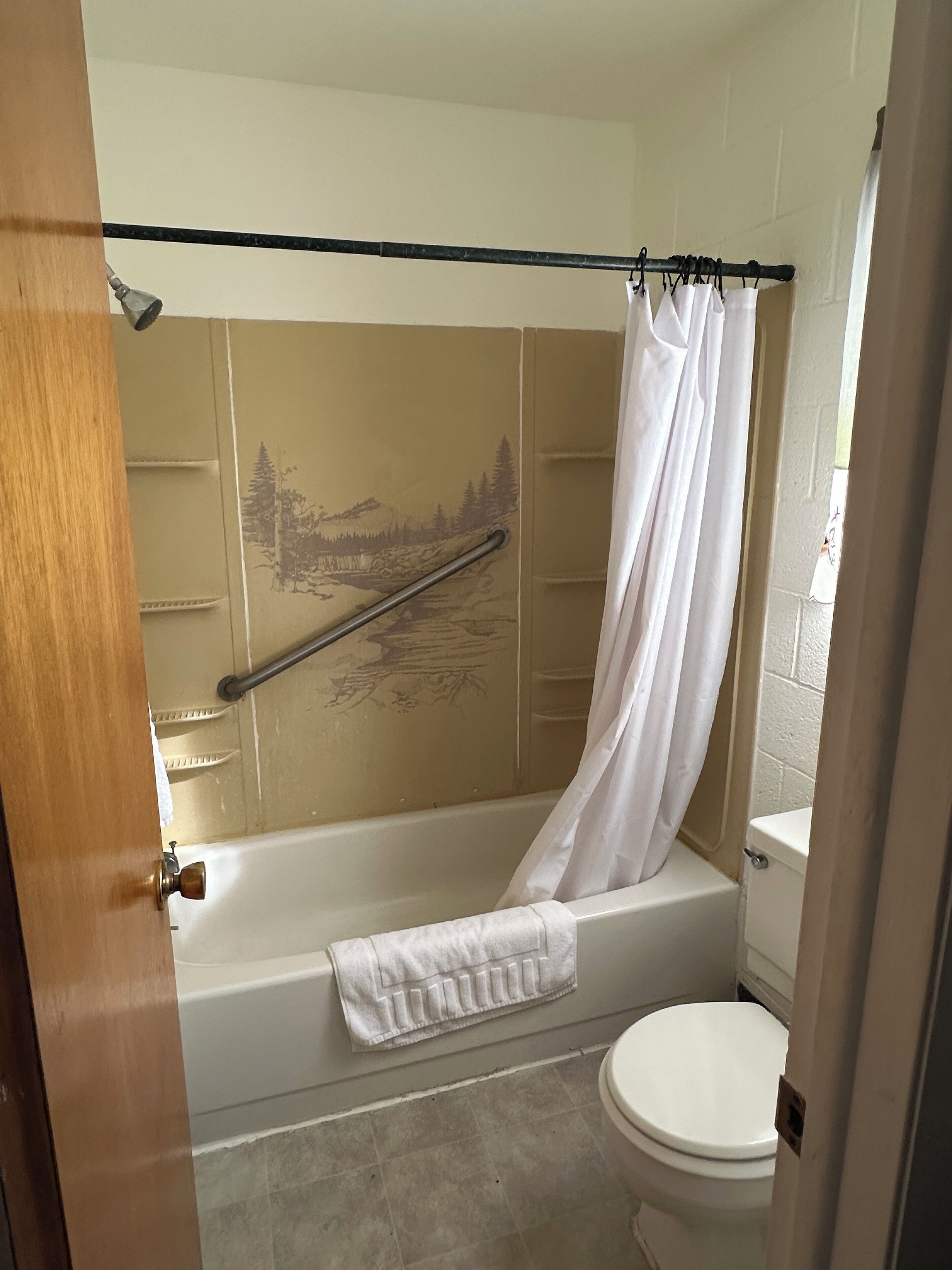 Un baño con bañera, cortina de ducha, toalla y retrete.
