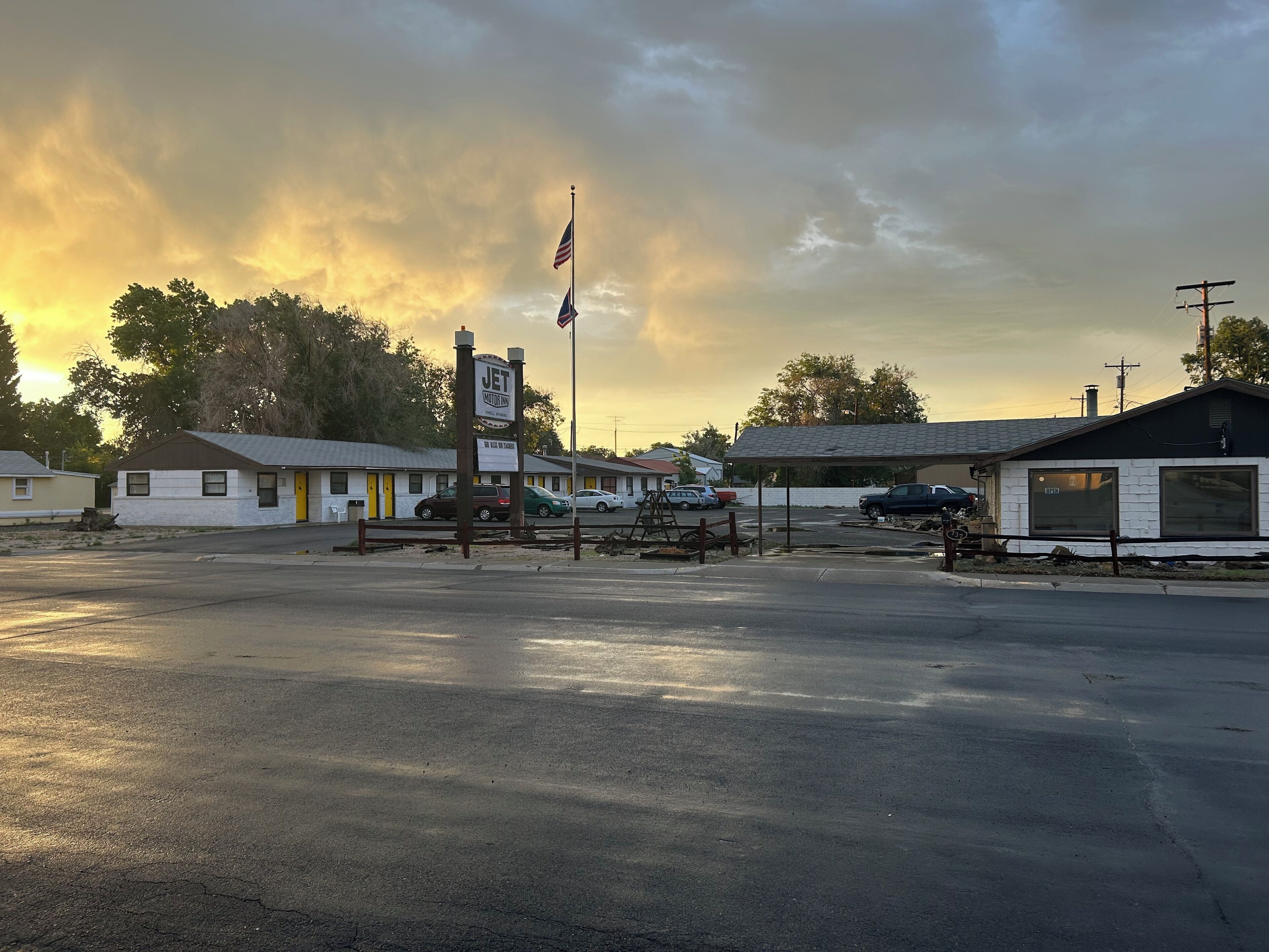 A motel with a signboard, a flag, and a parking lot.