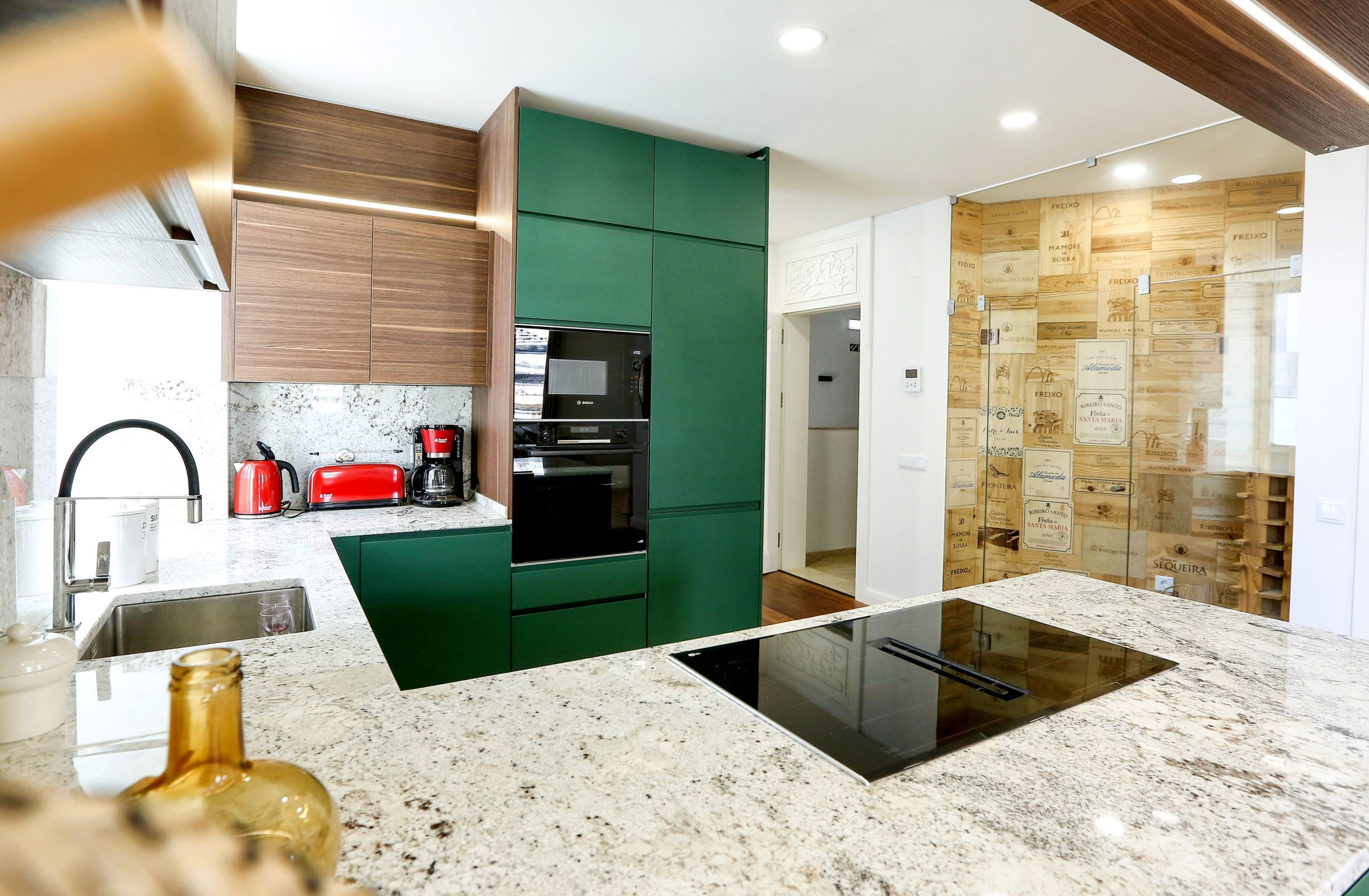 A modern kitchen with green cabinets, a black oven, and a built-in microwave.