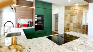 A modern kitchen with green cabinets, a black oven, and a built-in microwave. - Green Essence Duplex in Faro by Misha s Place (Faro)