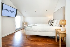 Una camera da letto con un letto, un comodino, una TV a muro e una finestra.