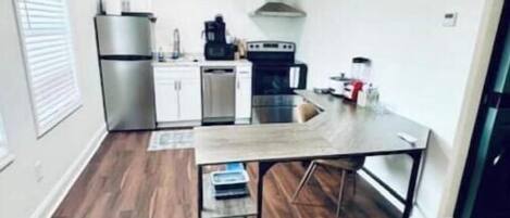 Una cocina compacta con electrodomésticos modernos, un comedor con mesa de madera y un horno empotrado.