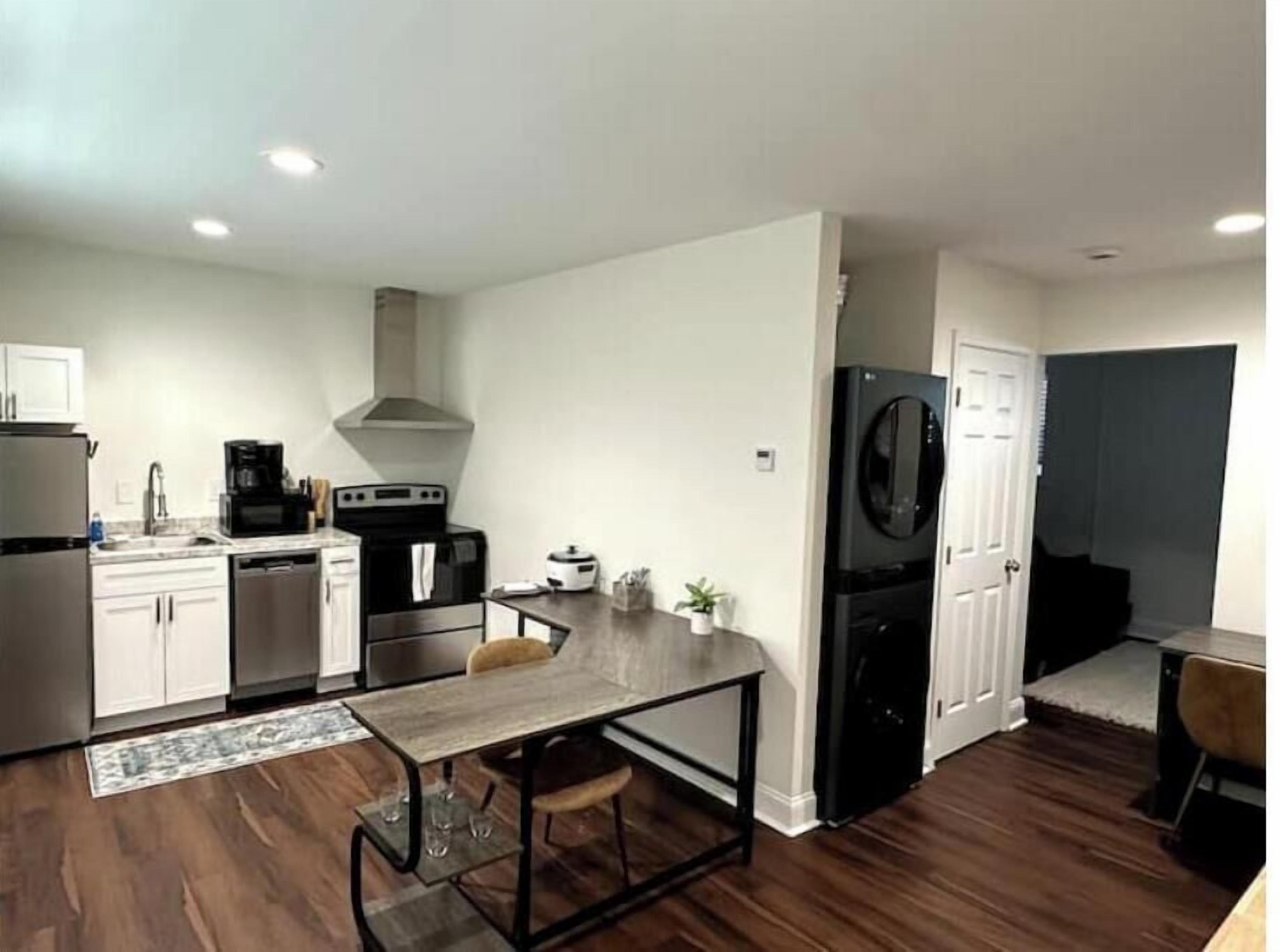 Una cocina compacta con armarios blancos, un refrigerador negro y un microondas.