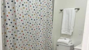 Ein Badezimmer mit Vorhang mit Punkten, Toilette, Waschbecken und Handtuchhalter.