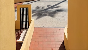 Un patio con una palmera, suelo de baldosas y edificios al fondo.