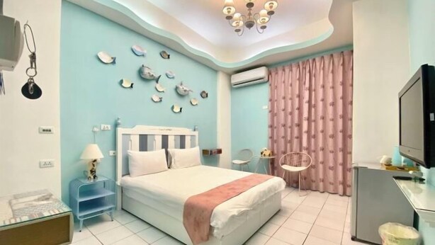 A bedroom with a bed, bedside tables, a TV, and a wall with decorative fish. - Hualian Dawan (Hualien)
