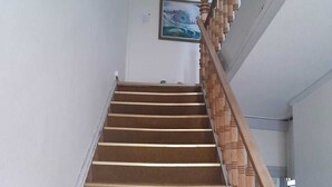 A wooden staircase with a handrail, leading to a landing with a framed picture on the wall. - Apartments in the heart of Hojer (Højer)