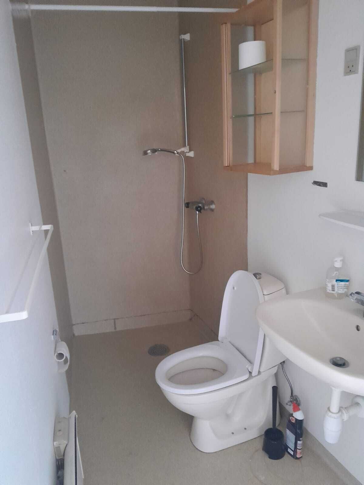 Un baño pequeño con inodoro, lavamanos y ducha.