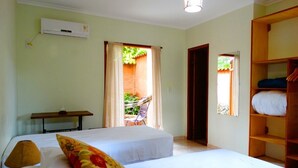 A hotel room with two beds, a wooden wardrobe, a table with a lamp, and a window with curtains. - Pousada Bothanica (Pirenópolis)