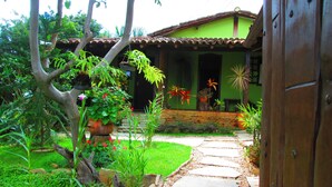 A garden pathway leading to a house with a green facade and a tiled roof. - Pousada Bothanica (Pirenópolis)