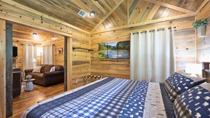 A wooden cabin interior with a bed, a sofa, and a small table. - Private Couples' Retreat Near Beavers Bend (Broken Bow)