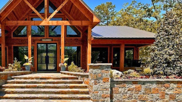 A wooden lodge with a stone entrance and a clear blue sky. - Private Couples' Retreat Near Beavers Bend (Broken Bow)