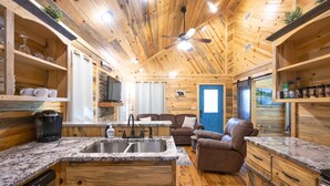 A wooden cabin interior with a kitchen, dining area, and living room. - Private Couples' Retreat Near Beavers Bend (Broken Bow)