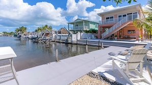 A waterfront property with a pool, outdoor seating, and a boat dock. - Snowbird Paradise - New Vacation Home in Key Largo (Key Largo)